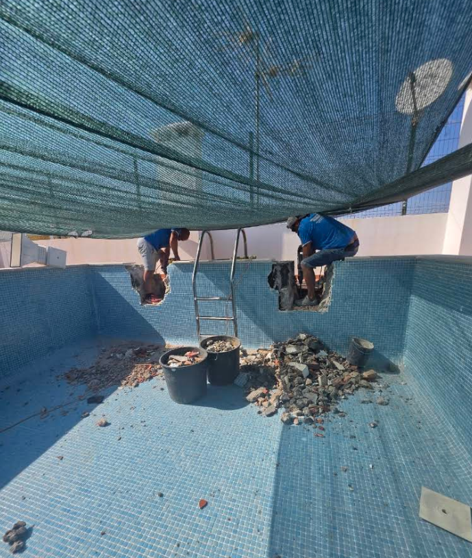 Trabalhadores a reparar o interior de uma piscina